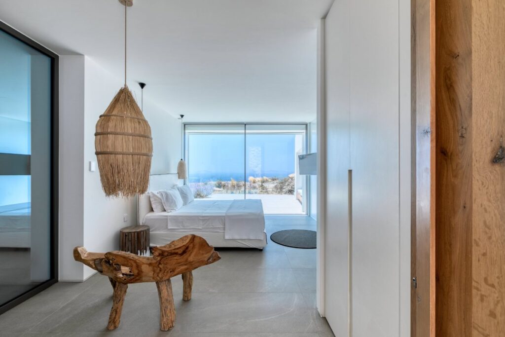 White walls, modern bedroom, and spacious bed in Mykonos luxurious rental villa.