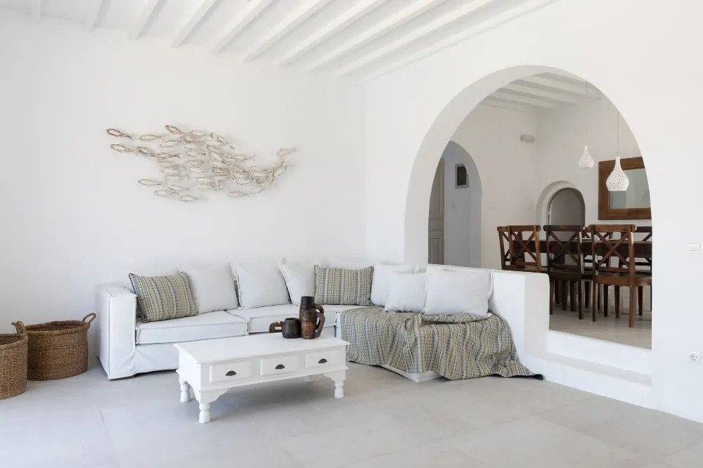 Cozy atmosphere in the modern living room with a comfortable sofa, soft pillows, and mini wooden table in Mykonos exceptional villa for rent.
