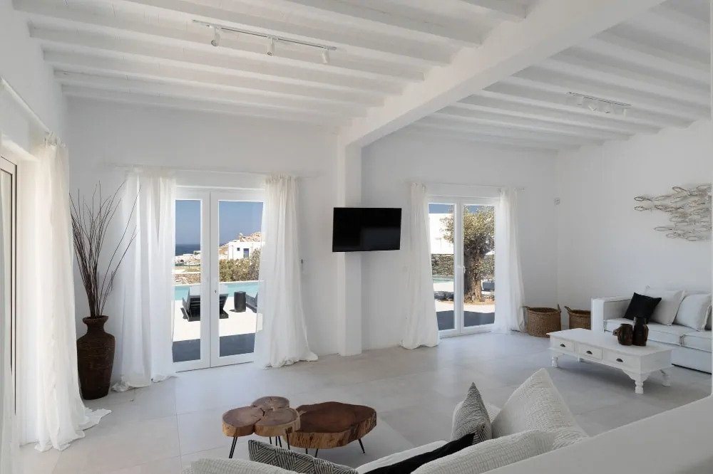 Bright spacious living room with white furniture and clear blue sea view in Mykonos best luxury rental villa