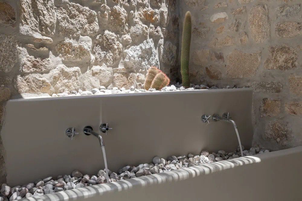 Drinking fountain in stone and ceramics in a modern garden of a private rental home in Mykonos, Greece.