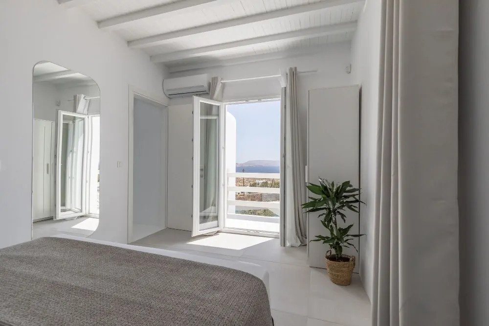 Mykonos luxurious villa’s comfortable bedroom with an exit to the terrace that offers a wonderful wide sea view.