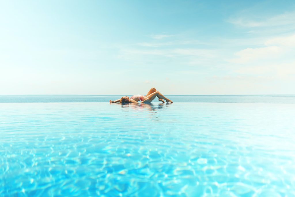 Girl lying at the edge of an infinity pool
