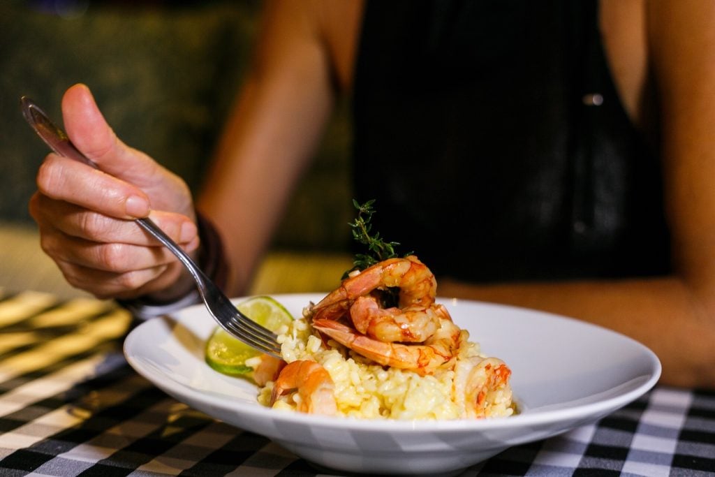 Person eating a shrimp risotto dish