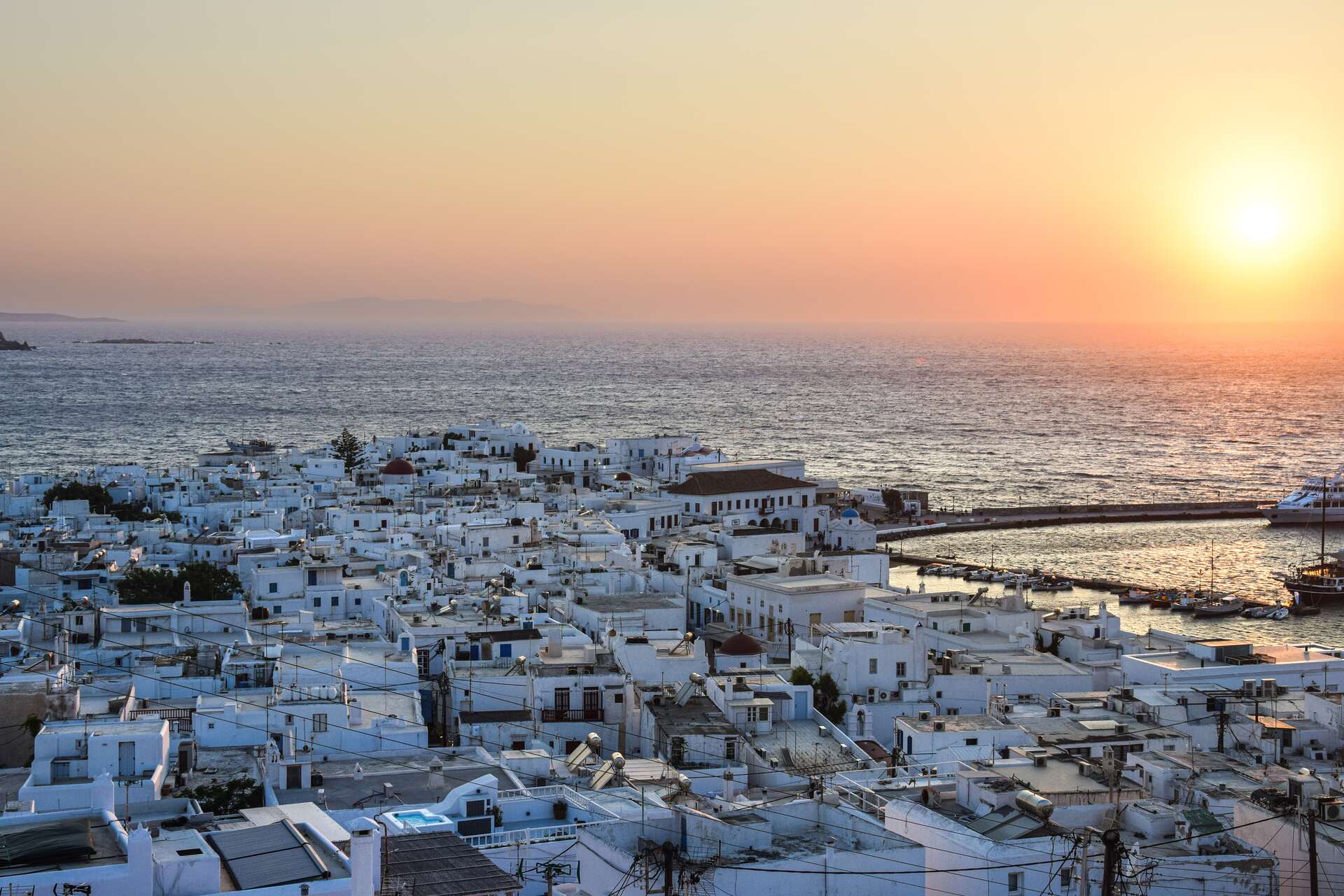 The view of local houses and Mykonos villas for rent from above during the sunset