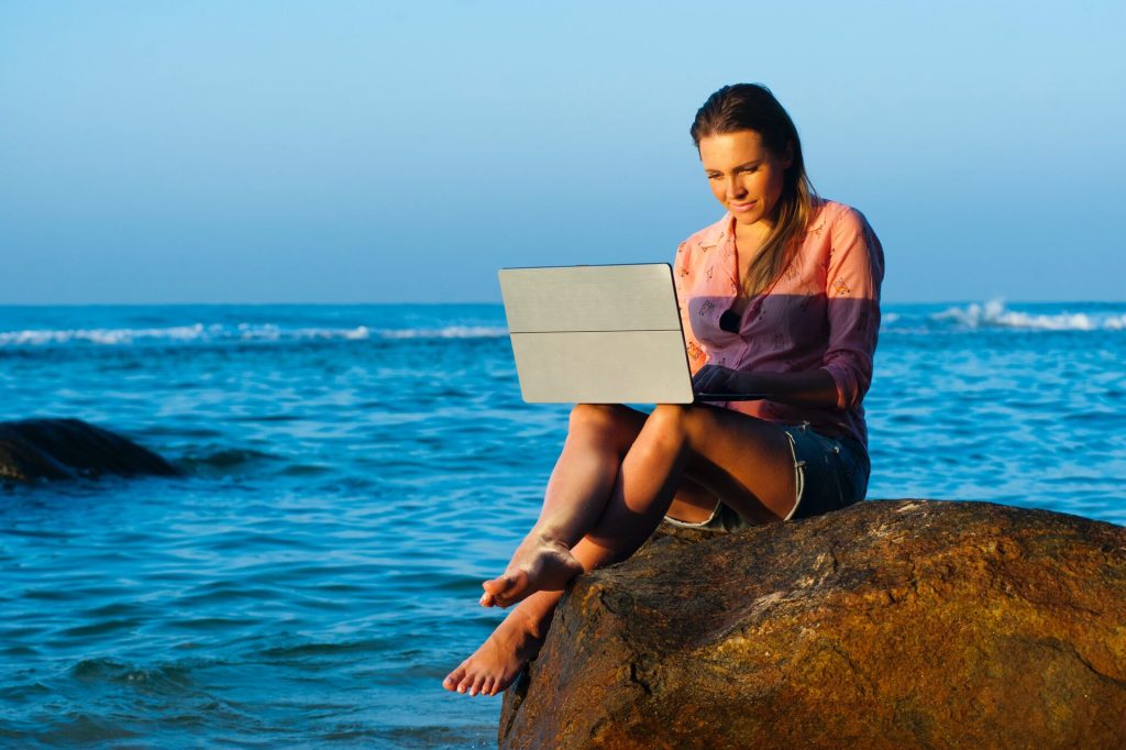 Woman sitting on a rock and working on her laptop