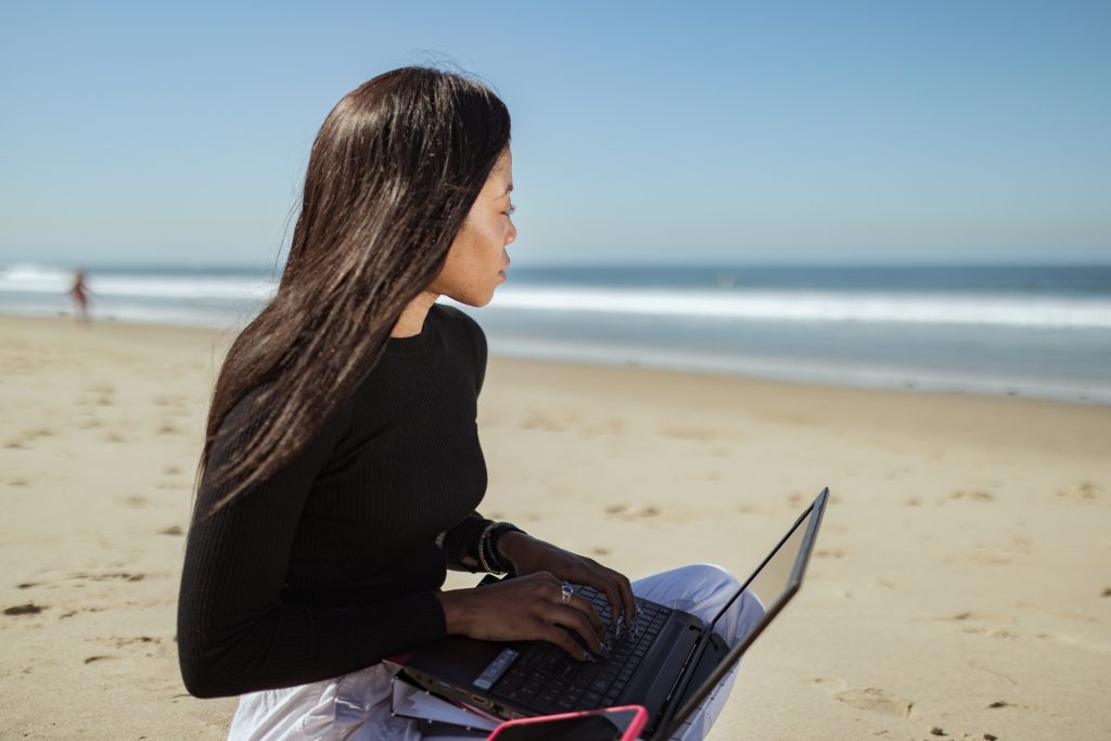 Woman typing on a laptop and looking at the sea