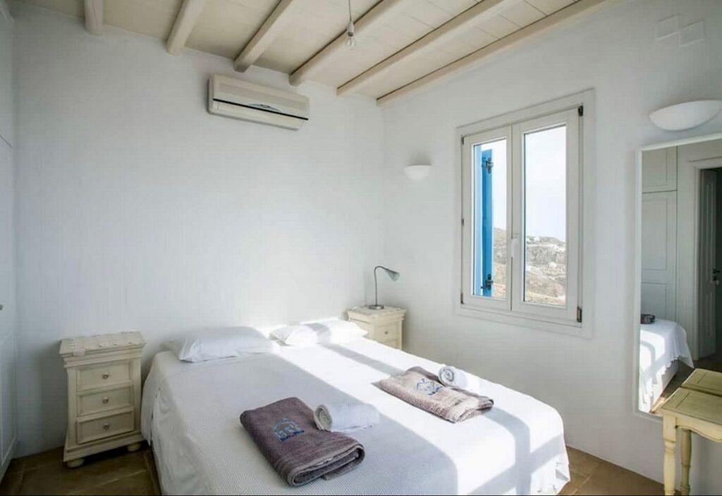 Bedroom with white walls and high ceiling in Mykonos lavish villa for rent.
