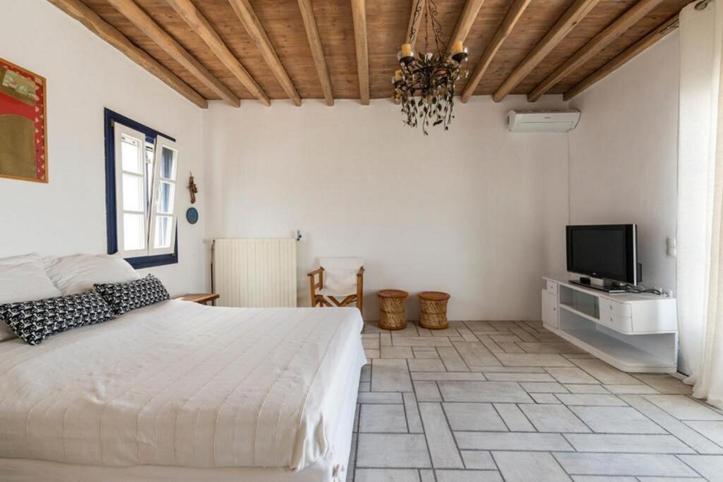 High wooden ceiling, boho decoration, and comfy beds in Mykonos lavish villa for rent.