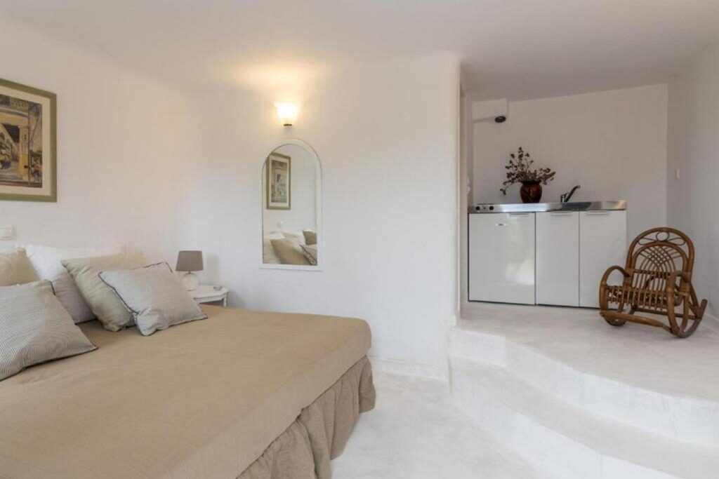 Comfortable bed in a spacious bedroom with white and creamy design, Mykonos villa for booking.