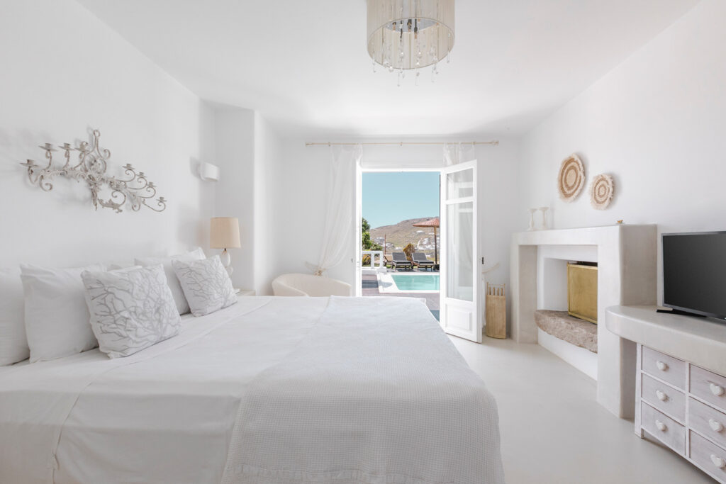Comfort and elegance in Mykonos' top rental villa's bedroom with a terrace and swimming pool.
