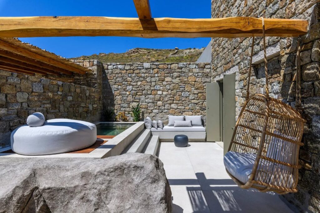 Sofa, swing, cushion, and outside spa in Mykonos lavish villa for rent.