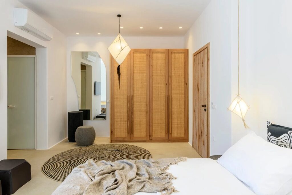 Spacious bedroom with modern furniture in Mykonos splendid villa for booking.