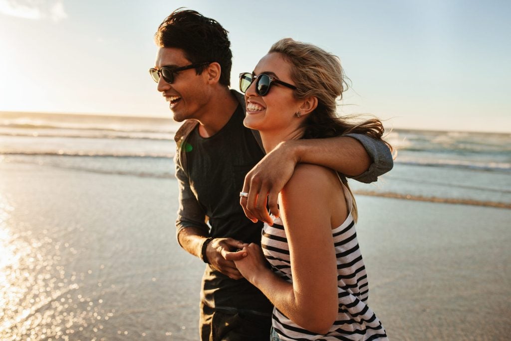 Smiling young couple walking on the beach