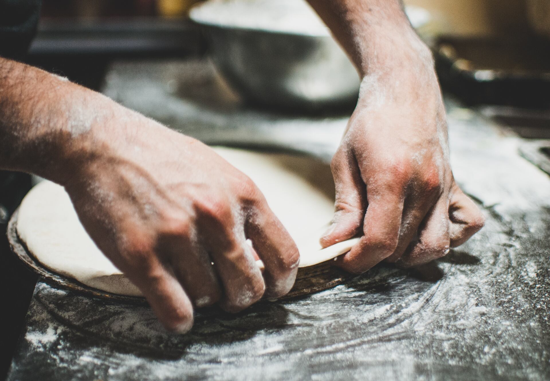 A person preparing pizza dough