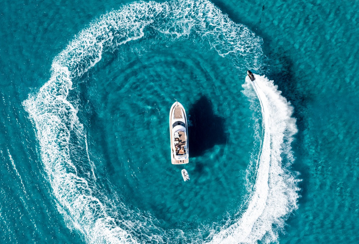 A yacht at sea and a boat sailing around it 