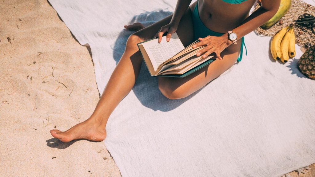 Woman in a blue bikini reading on a beach