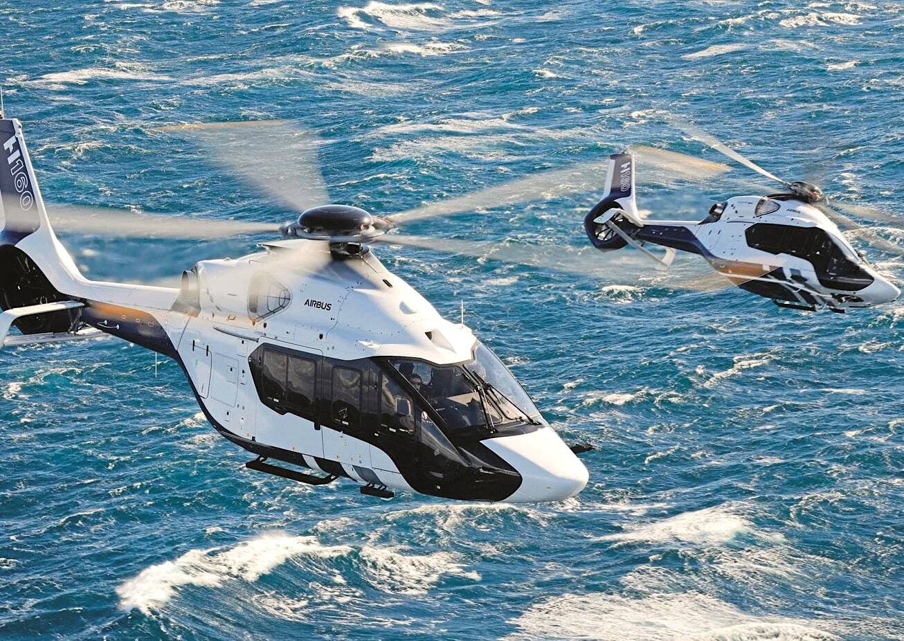 Two helicopters flying above the sea
