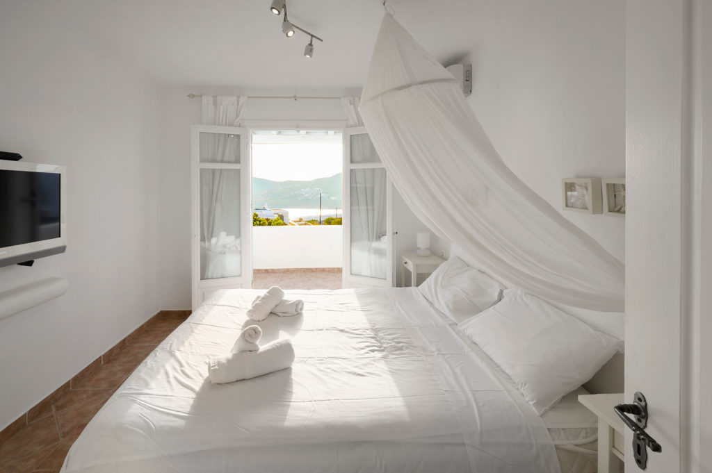 White, elegant curtains and a bright bedroom in Mykonos villa are available for rent.