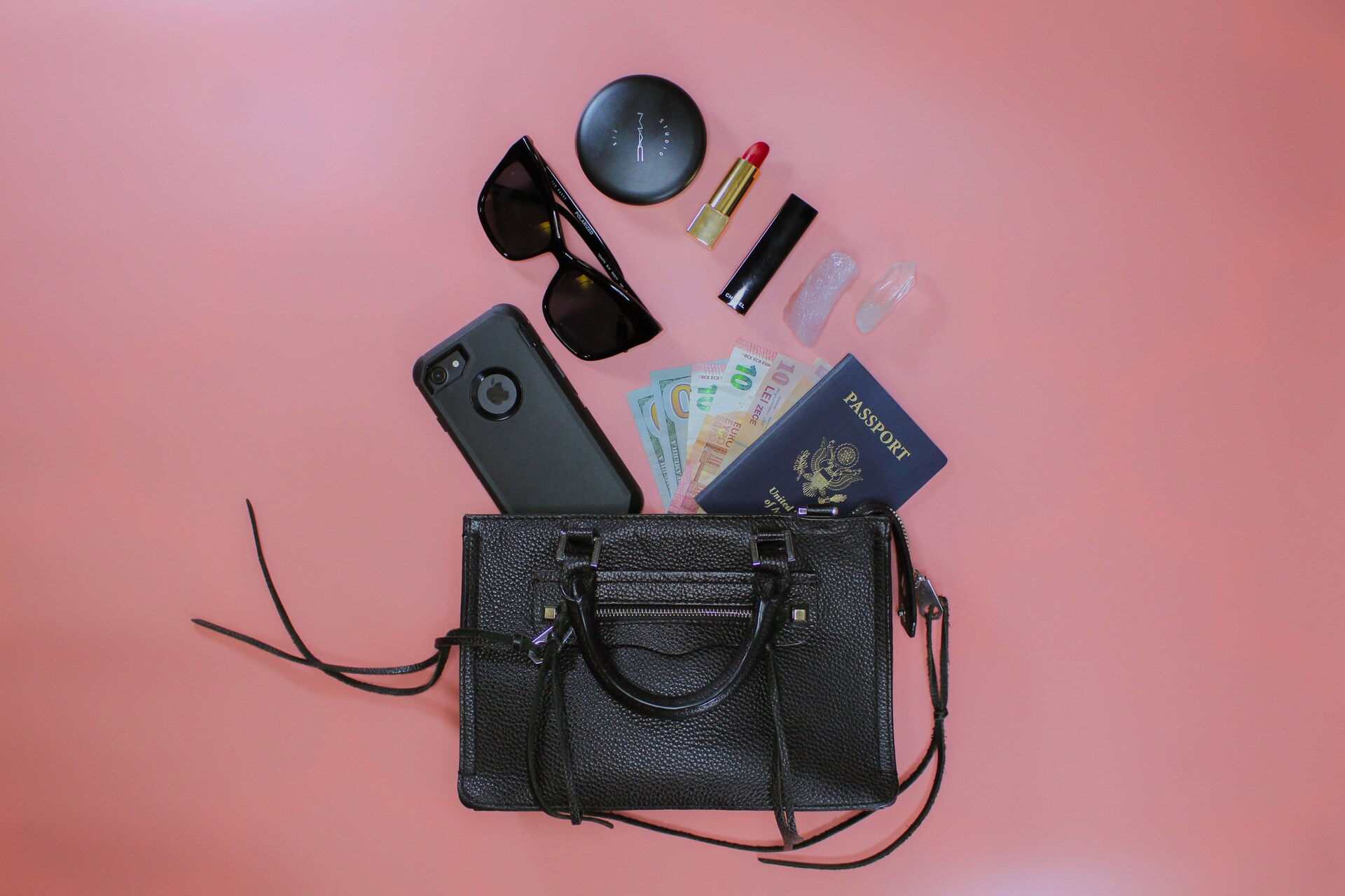 A black handbag with a passport, money, phone, and makeup
