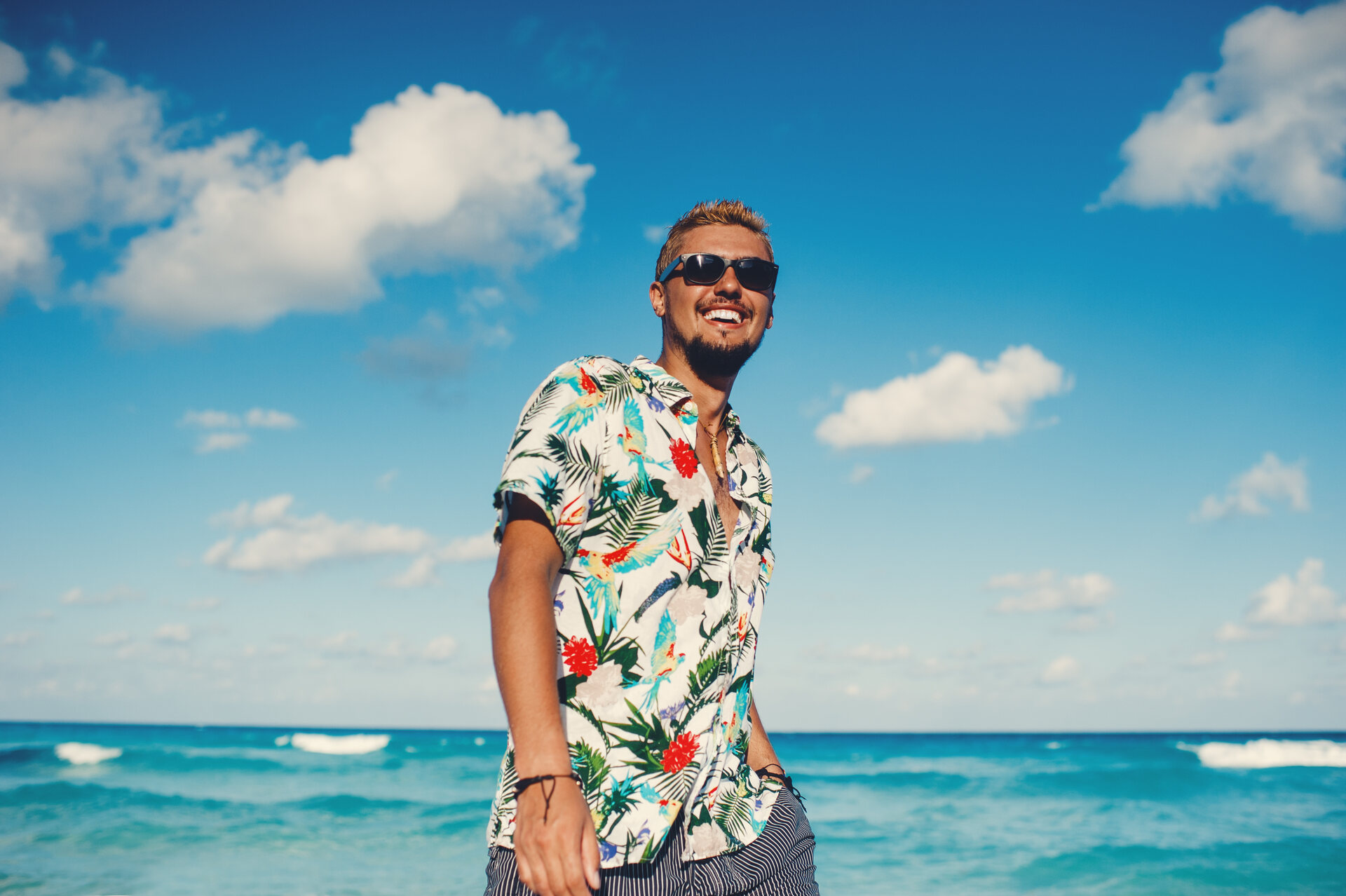A man in a Hawaiian shirt on a beach