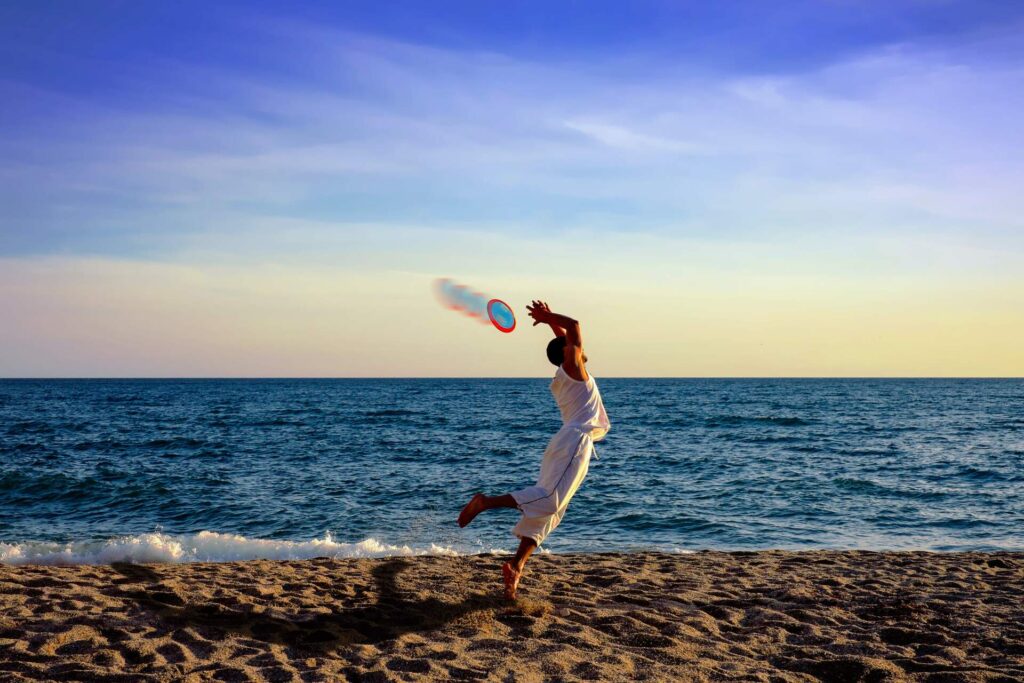 A person catching a frisbee on the beach