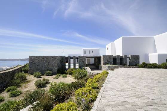 Villa Elizabeth, Aleomandra, Mykonos, day exterior, white buildings, stone walls, nature, bushes, blue sky, panoramic sea view
