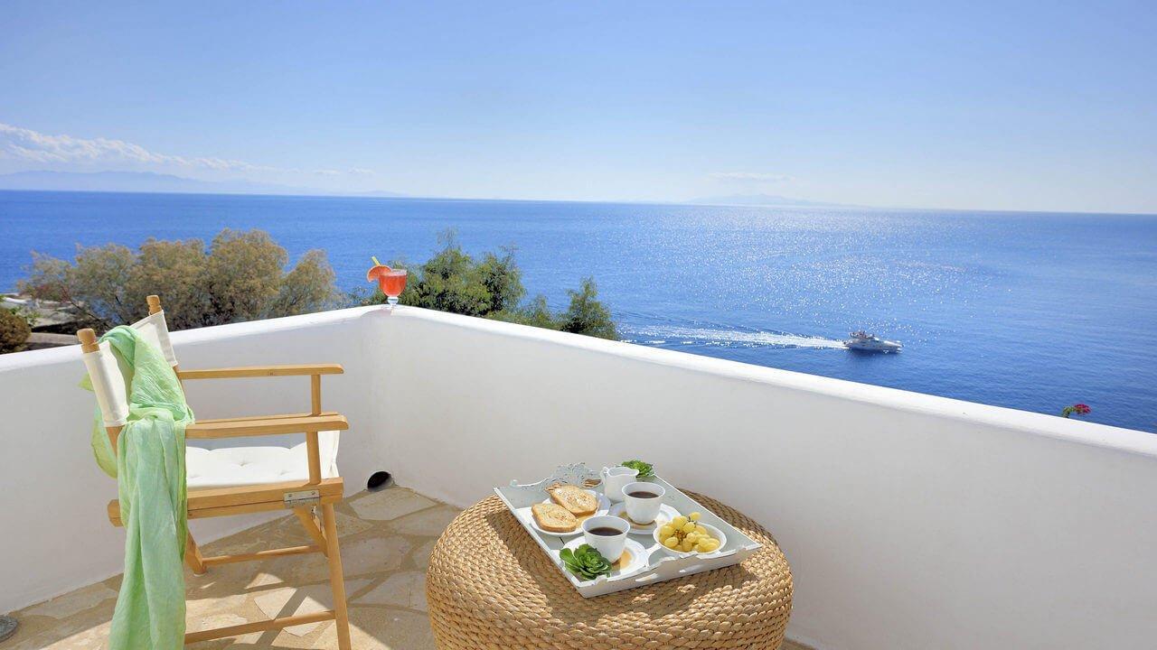 A terrace overlooking the sea with a coffee table and breakfast