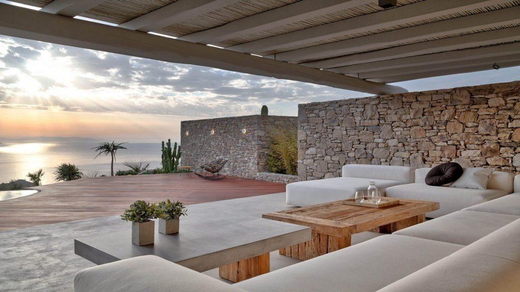 Villa Aphrodite, Agia Sofia, Mykonos, porch, rest area, sofa, coffee table. stone wall. deck. nature, panoramic sea view