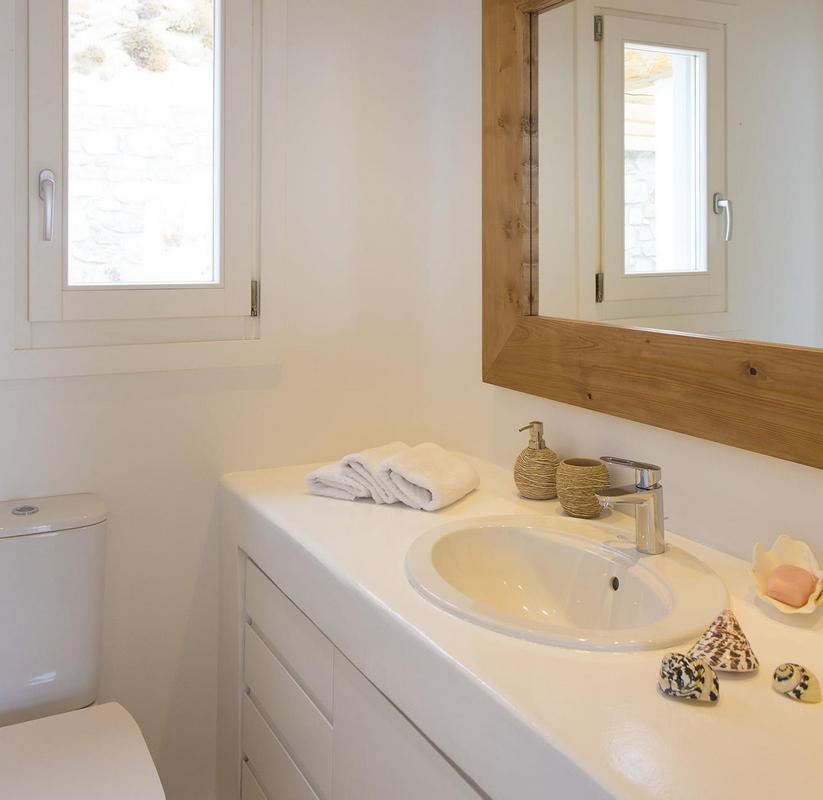 white bathroom walls with wooden frame mirror and sink
