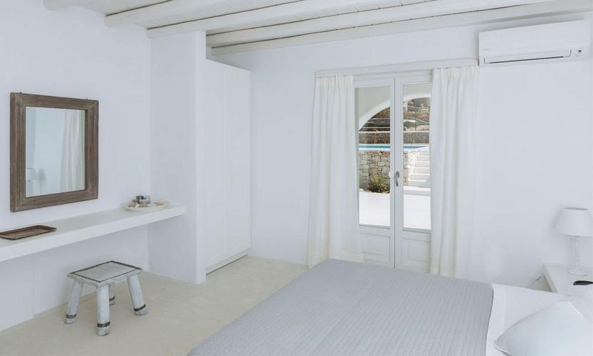 white wall bedroom with soft bed and stool in front of mirror