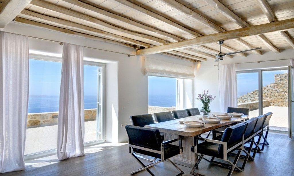 Villa Gianna, Fanari, Mykonos, Dining room, Chairs, Table, Flowers, Fan, Sky, Sea view, Stone wall, Wooden floor