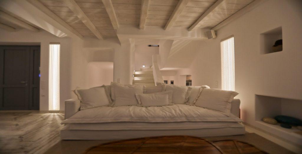 Villa-Ragnar_12.jpg Kalafatis Mykonos, living room, sofa, pillows, tables, stairs, door