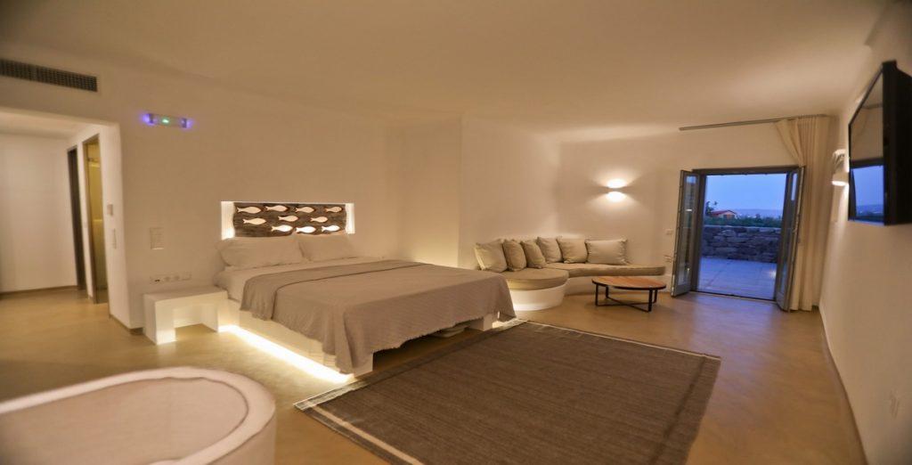 Villa-Ragnar_17.jpg Kalafatis Mykonos, 1st bedroom, king size bed, nightstand, lights, sofa, pillows, flat screen TV, carpet