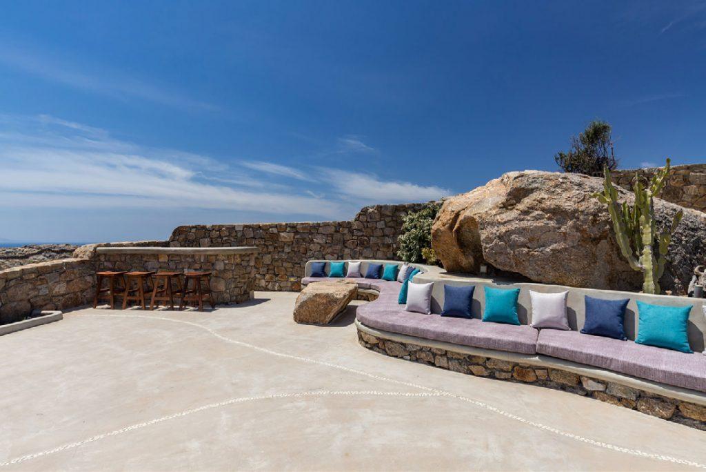 Villa-Camelia_10.jpg Agrari Mykonos, outdoor, bench, pillows, high chairs, bar, stone wall, sky