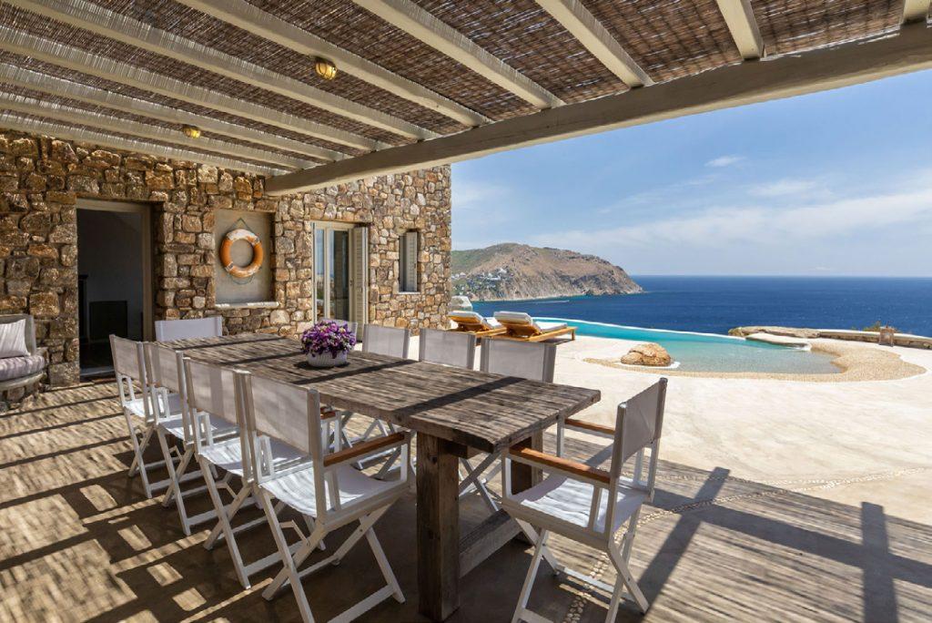 Villa-Camelia_13.jpg Agrari Mykonos, outdoor dining area, dining table, chairs, flowers, sea, sky, pool, climbers