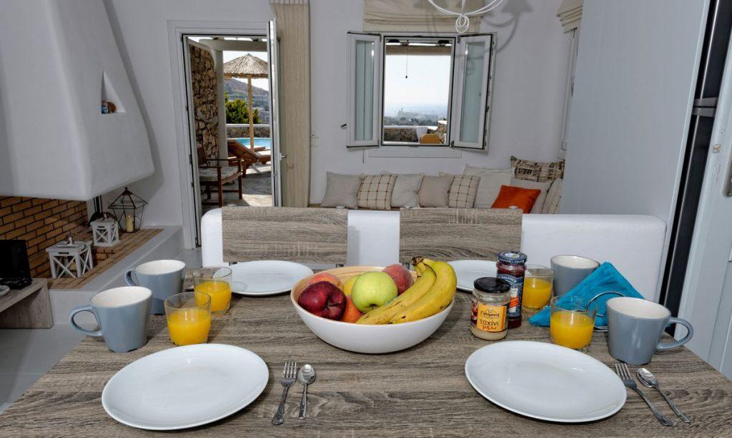 Villa-Valence-_19.jpg Kalafatis Mykonos, kitchen, dining table, fruits, bowl, plates, cups, spoons, forks, juice