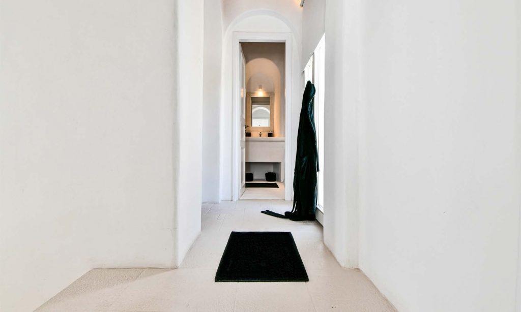 hallway to the bathroom with black carpet
