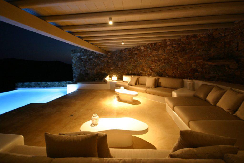 lit outdoor living area with comfort couch and unique designed tables