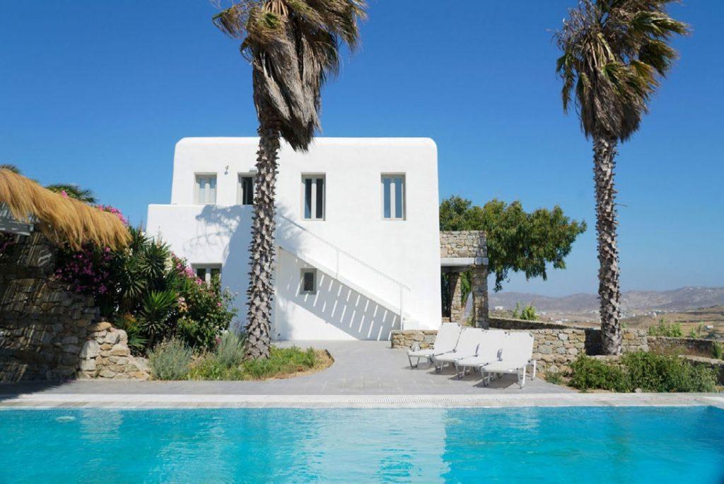 Villa Umabel, Agios Stefanos, Mykonos, Swimming pool, Pool, Stone wall, Balcony, Chairs, Lazy bag, Sky, White villa, Plams