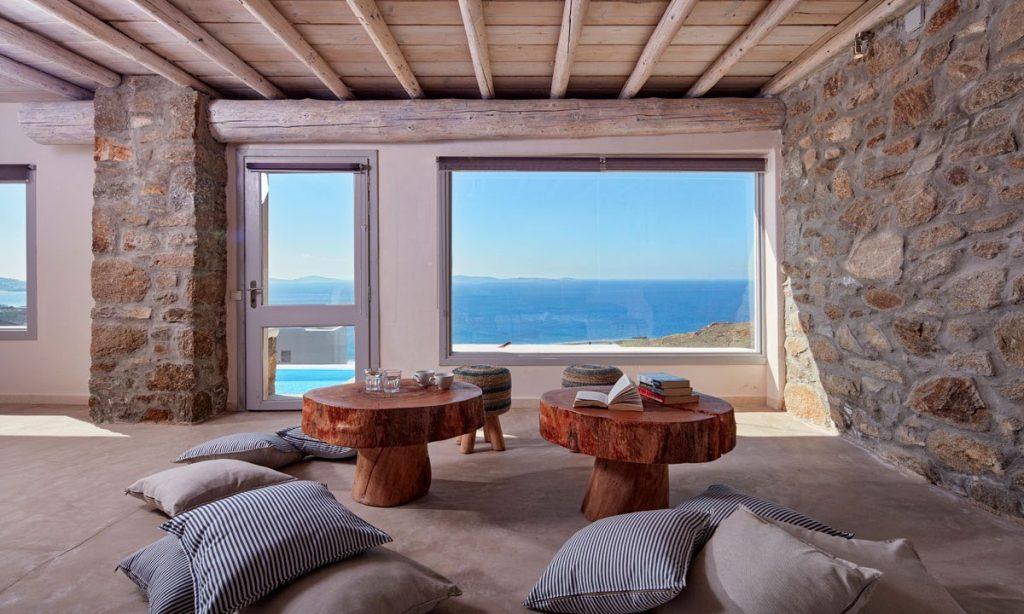 Villa Orion Retreat, Houlakia, Mykonos, interior, living room, pillows, carpet, tables, books, glasses, cups