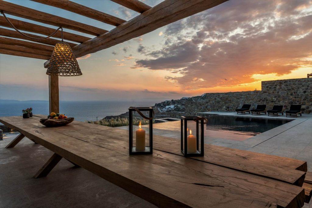 long wooden table and chairs to enjoy Mykonos sunset