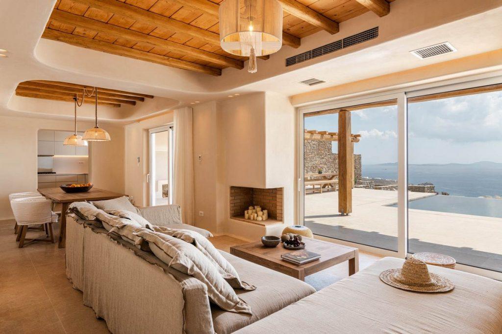 natural lightened spacious living room with big sofa and fireplace faced directly at window wall sea view