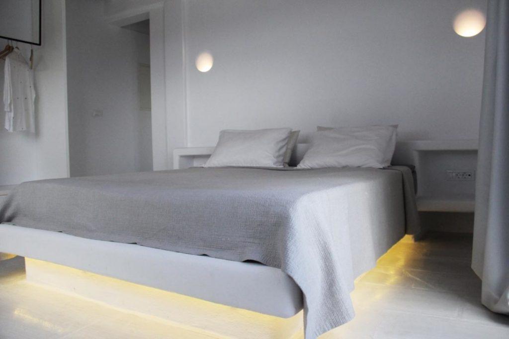 bedroom with grey sheets and lit bed