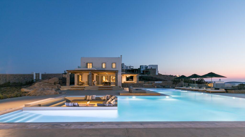 night view of a villa with a lighted pool and a view of the purple sky