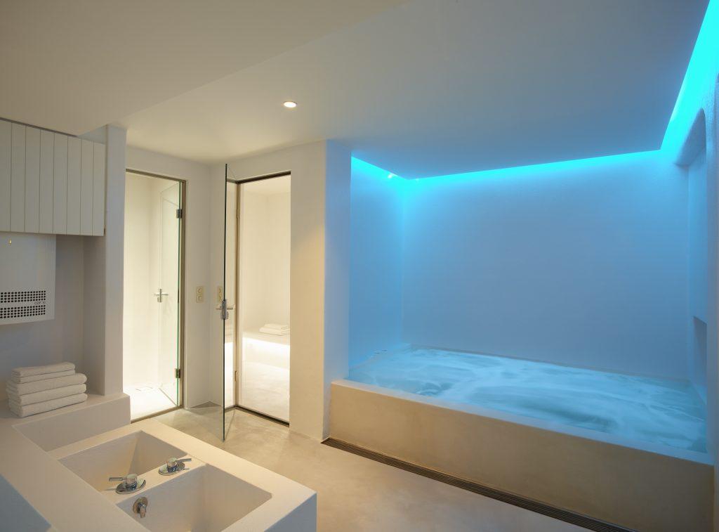 spacious led lamp illuminated bathroom with giant bathtub and shower cabins