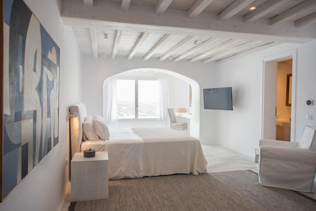 white walls of the bedroom with a beige bed and a wooden bedside table