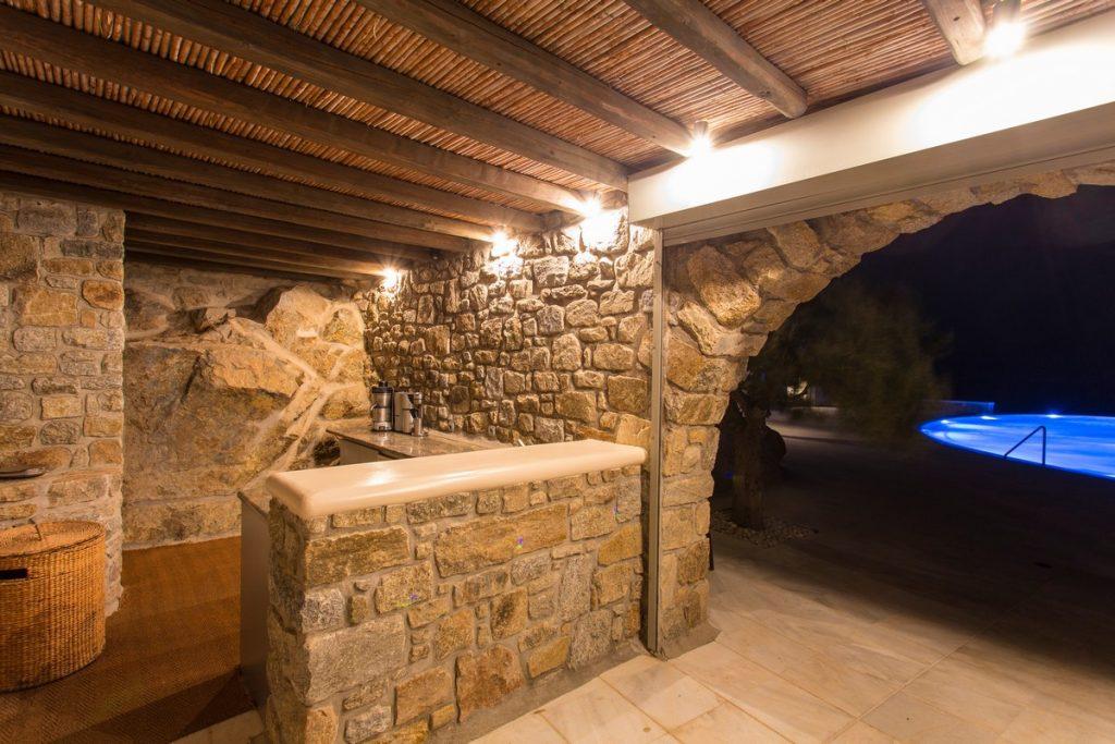 luxury stone bar with wooden canopy by the lighted pool