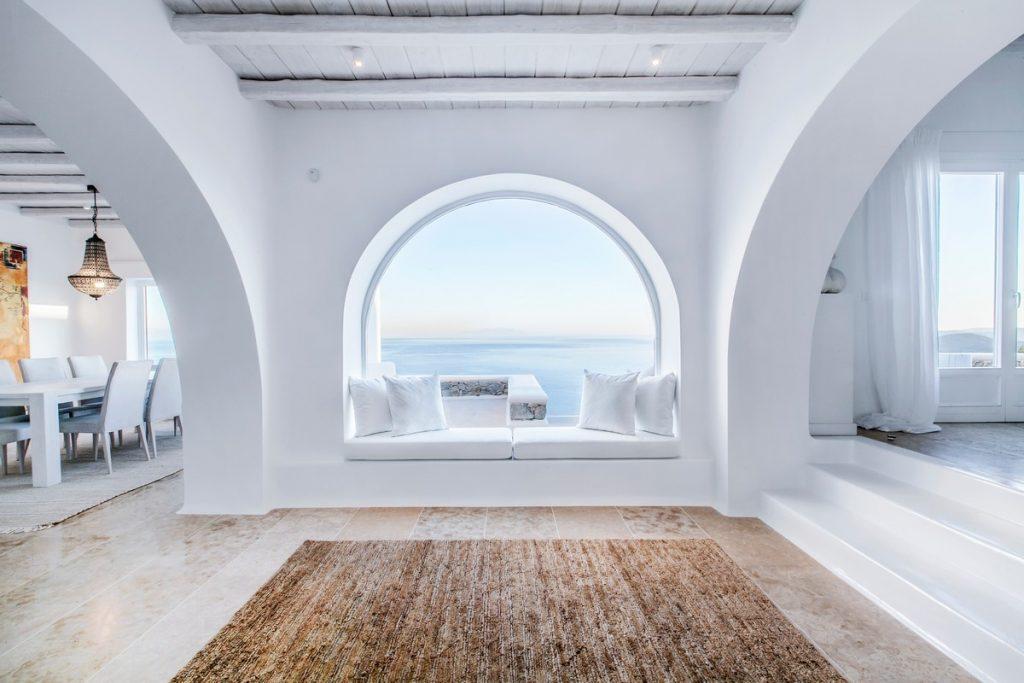 circular window with a comfortable sofa and a view of the glistening sea