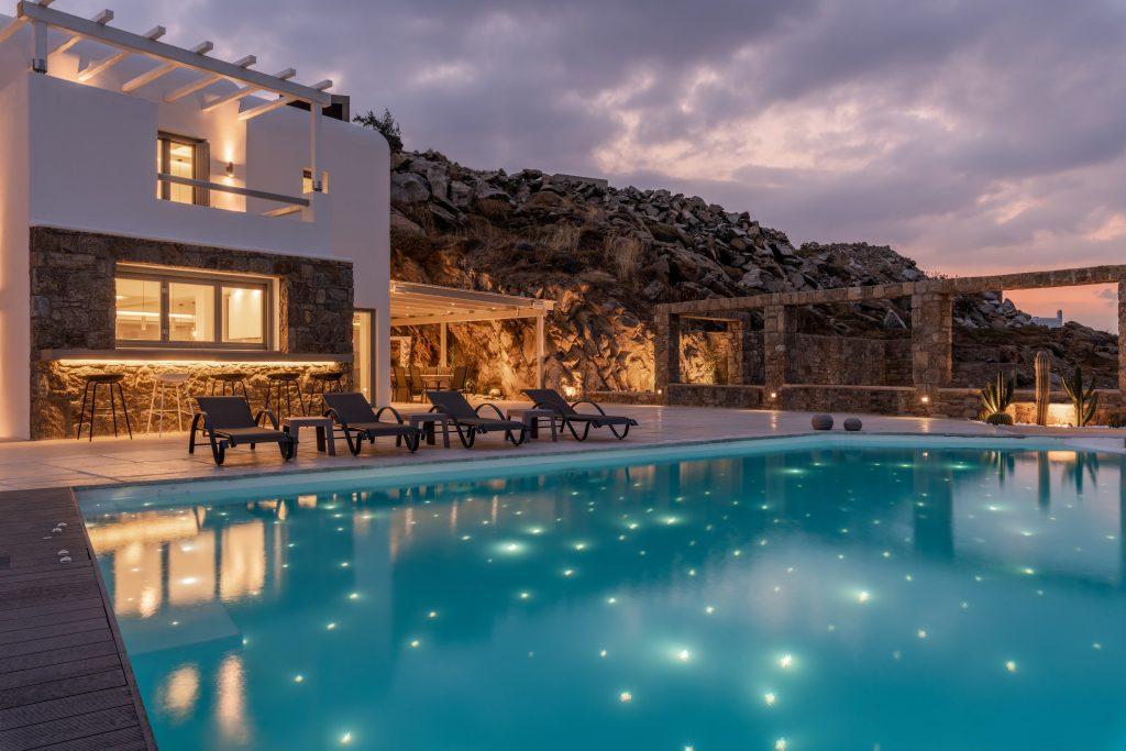 night view of a luxury villa with a pool lit by tiny lamps that give the appearance of stars