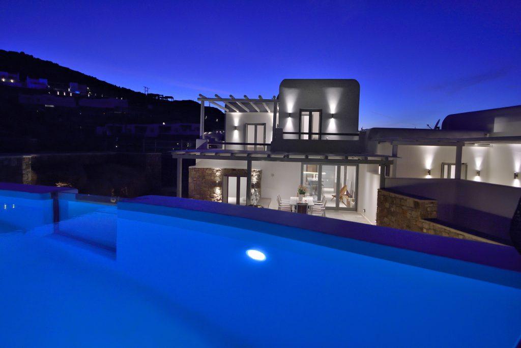 view of the blue sky and a reflection of the starry sky in the pool and lit villa